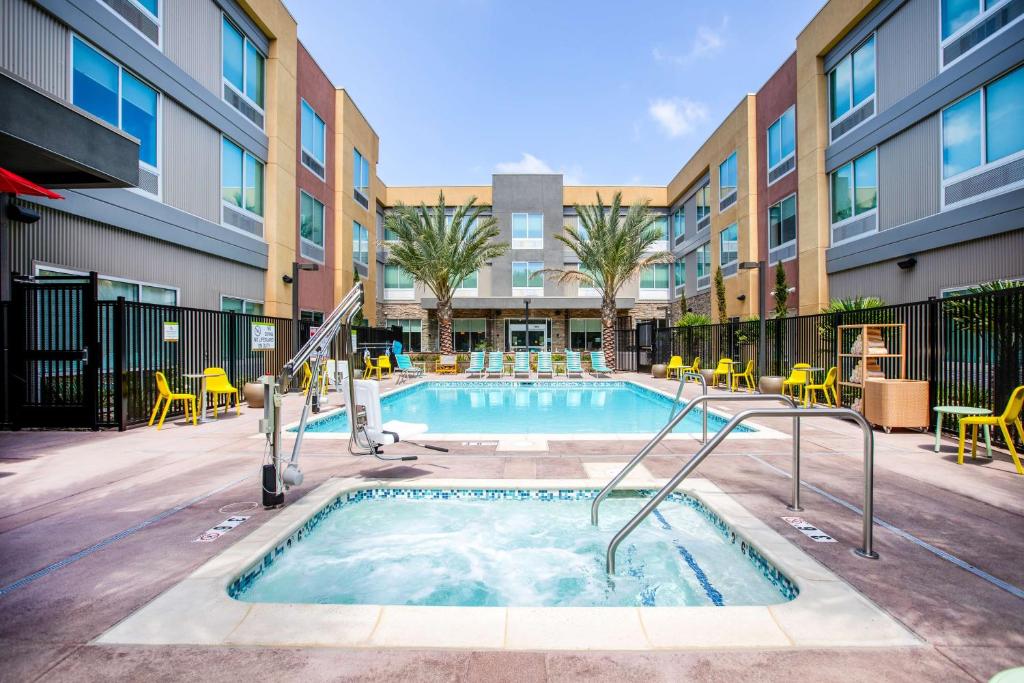卡爾斯巴德的住宿－Home2 Suites By Hilton Carlsbad, Ca，一座带椅子的游泳池以及一座建筑