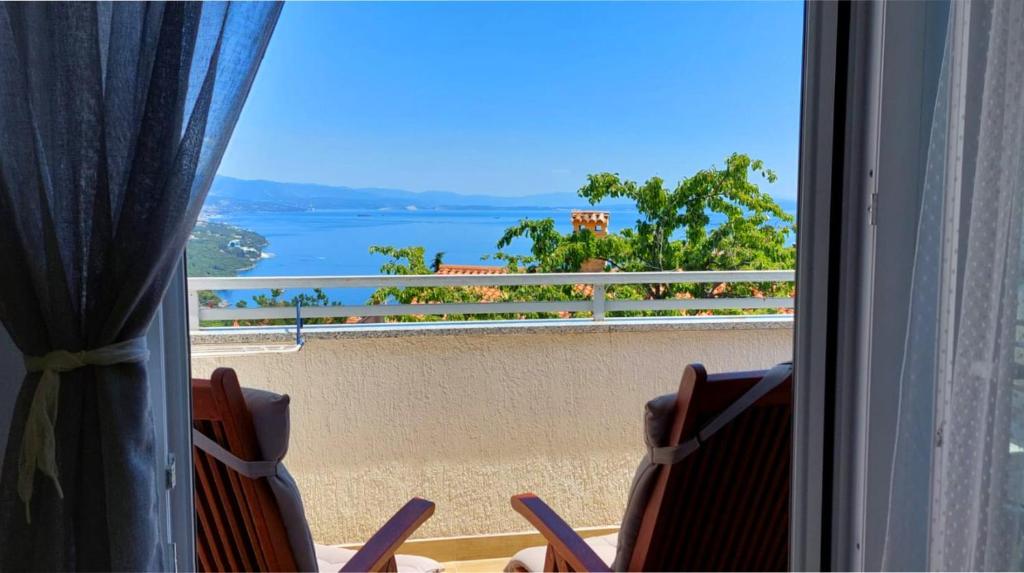 a view of a beach from a window with chairs at Milena Apartment Opatija in Volosko