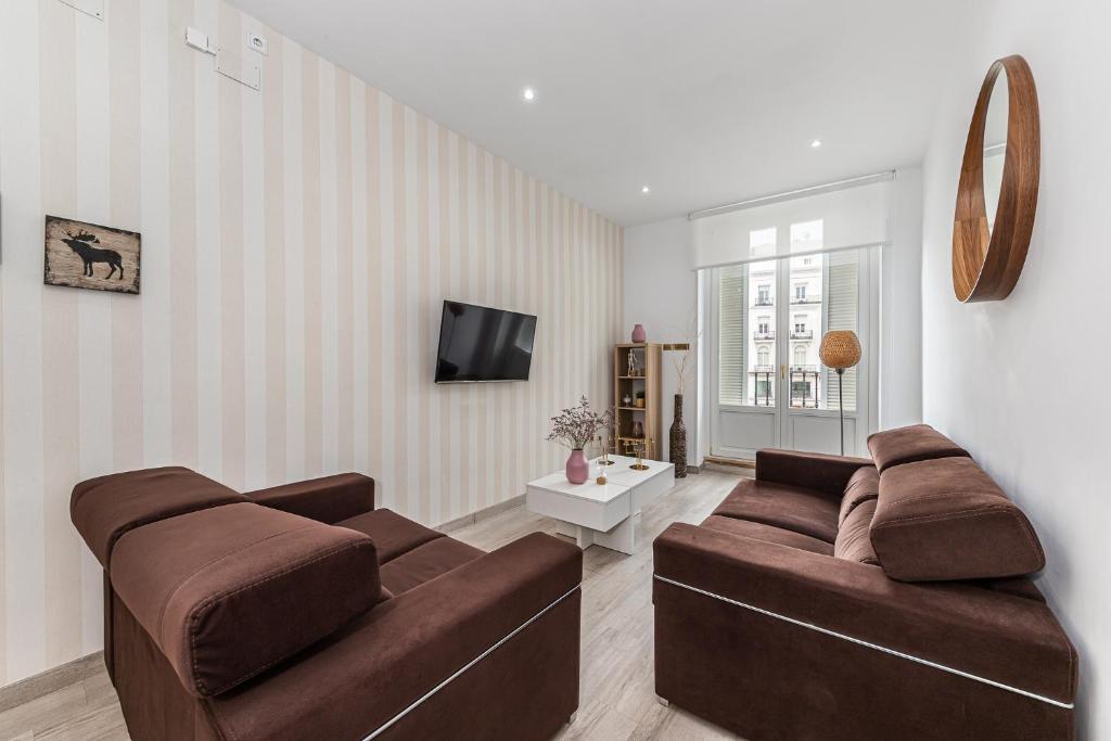sala de estar con 2 sofás marrones y TV en BNBHolder Apartamentos en Sol Confort 9 en Madrid