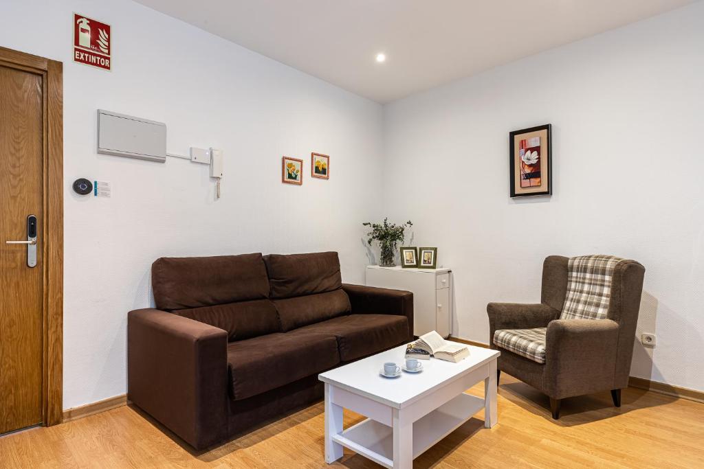 uma sala de estar com um sofá e uma cadeira em BNBHolder Apartamentos en Sol Confort 3 em Madri