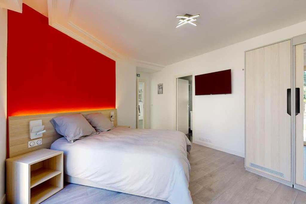 une chambre avec un grand lit avec un mur rouge dans l'établissement 03.Studio#Creteil#Loft#Cinéma#Terrasse, à Créteil