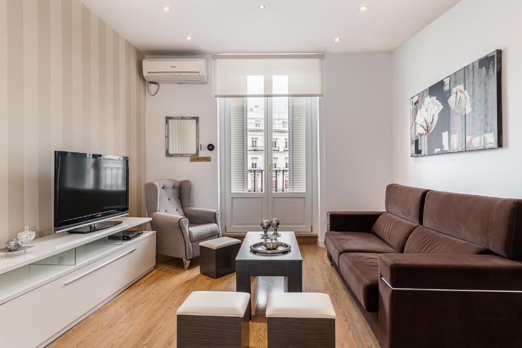uma sala de estar com um sofá e uma televisão em BNBHolder Apartamentos en Sol Superior 1 em Madri