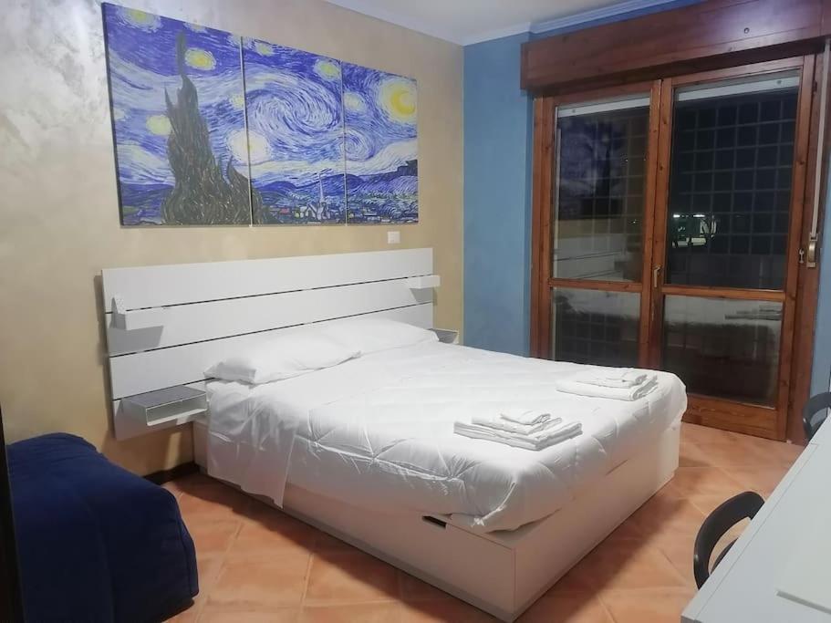 una camera con un letto bianco e un dipinto sul muro di Friend of all the world - Giardino di Roma - Casal Bernocchi - Acilia a Vitinia