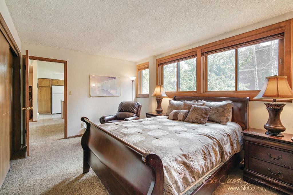 a bedroom with a bed and a chair and windows at A Perfect Location Walk to EVERYTHING Onsite Hot Tubs Grill And Pool SH52 in Breckenridge