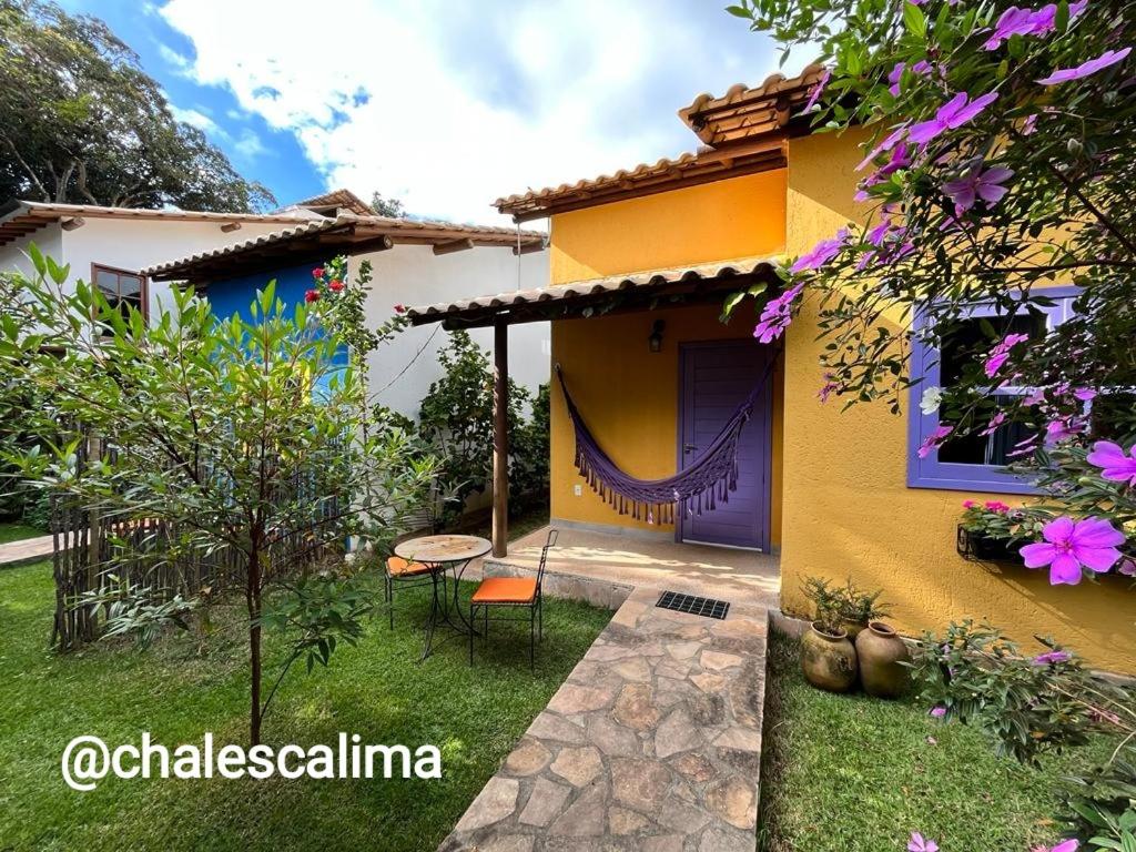 a yellow house with a purple door and a yard at Chalés Calima in Lençóis
