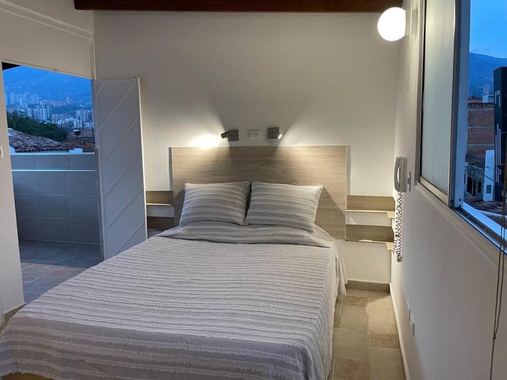 a bedroom with a large bed with a large window at Apartamento en San Marcos Envigado con Aire C, Balcón WIFI, Central y dotado in Envigado
