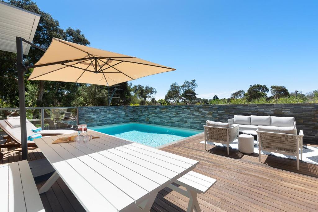 a patio with a table and an umbrella and a pool at Jetty Beach Retreat - Blairgowrie Luxury Family Retreat 5 Bed Heated Pool in Blairgowrie