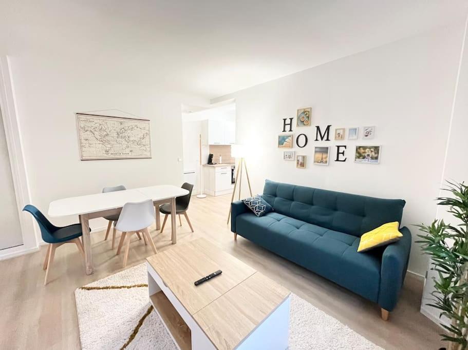 un salon avec un canapé bleu et une table dans l'établissement Charmant T2 au cœur de Bourges, à Bourges