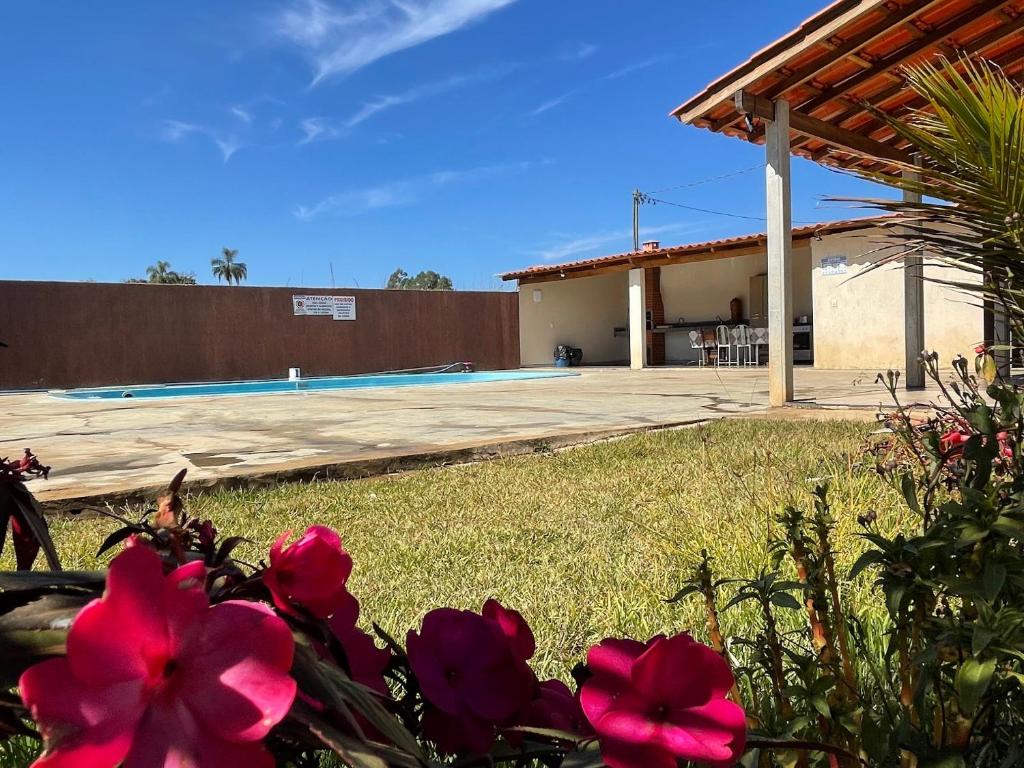 einen Garten mit rosa Blumen und einem Pool in der Unterkunft Rancho do Tomate in São Roque de Minas