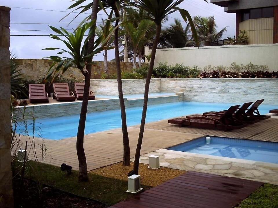 a swimming pool with two palm trees and a cat next to it at hihome - Mandai Flat in Cabo Frio