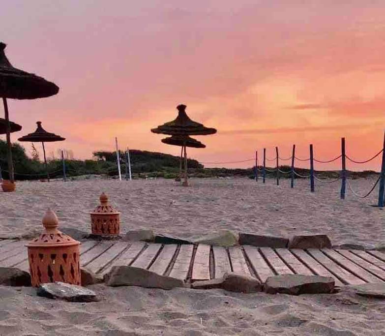 una playa de arena con sombrillas y una terraza de madera en Appartement pieds dans l’eau Tamaris, en Casablanca