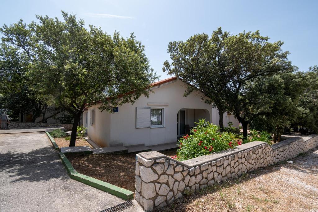 a small white house with trees and a stone wall at Apartments with a parking space Mandre, Pag - 16836 in Mandre