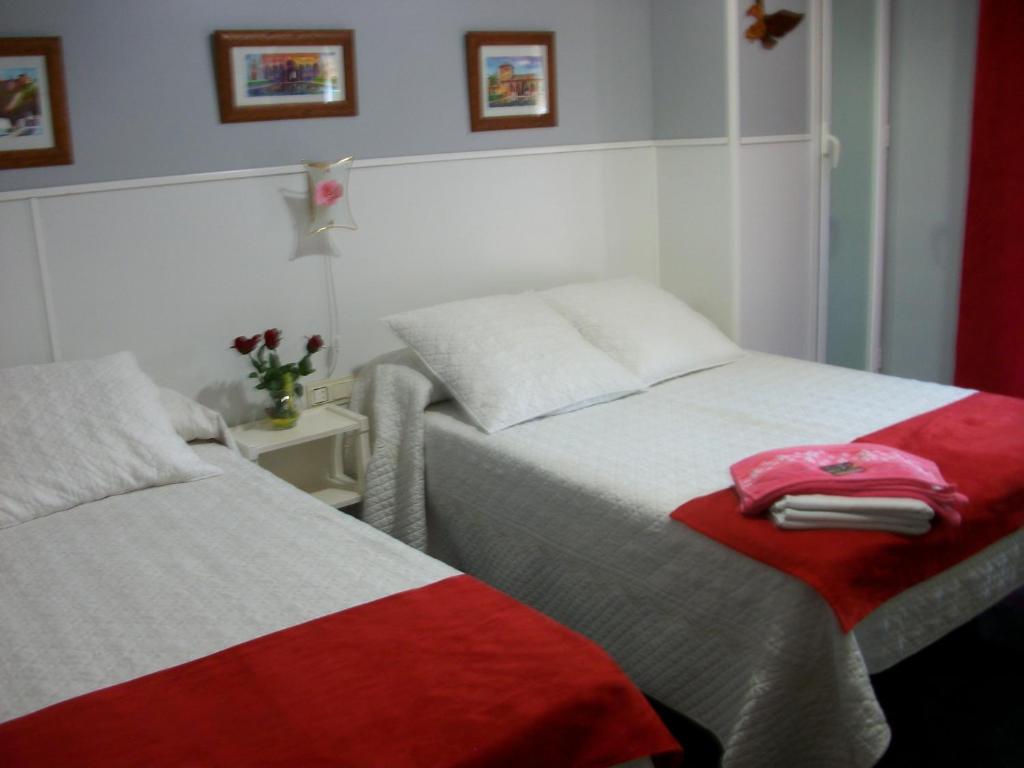a bedroom with two beds with red and white at Pensión Moni Albayzin in Granada