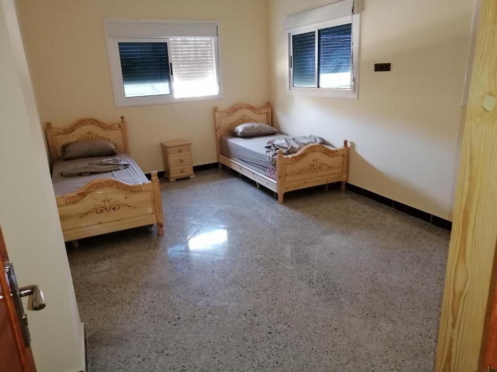 twee bedden in een kamer met twee ramen bij Bokidan in Al Hoceïma