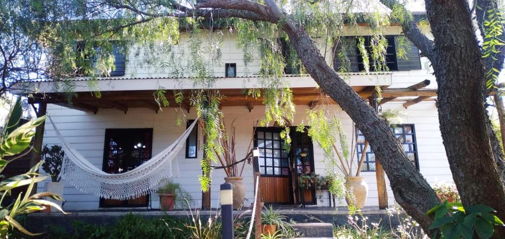 een wit huis met een boom ervoor bij Cabaña Raices in Unquillo