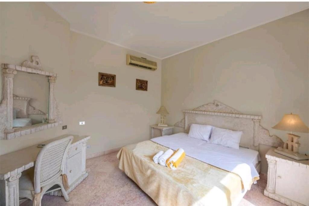 Habitación blanca con cama, escritorio y escritorio. en الجونه, en Hurghada