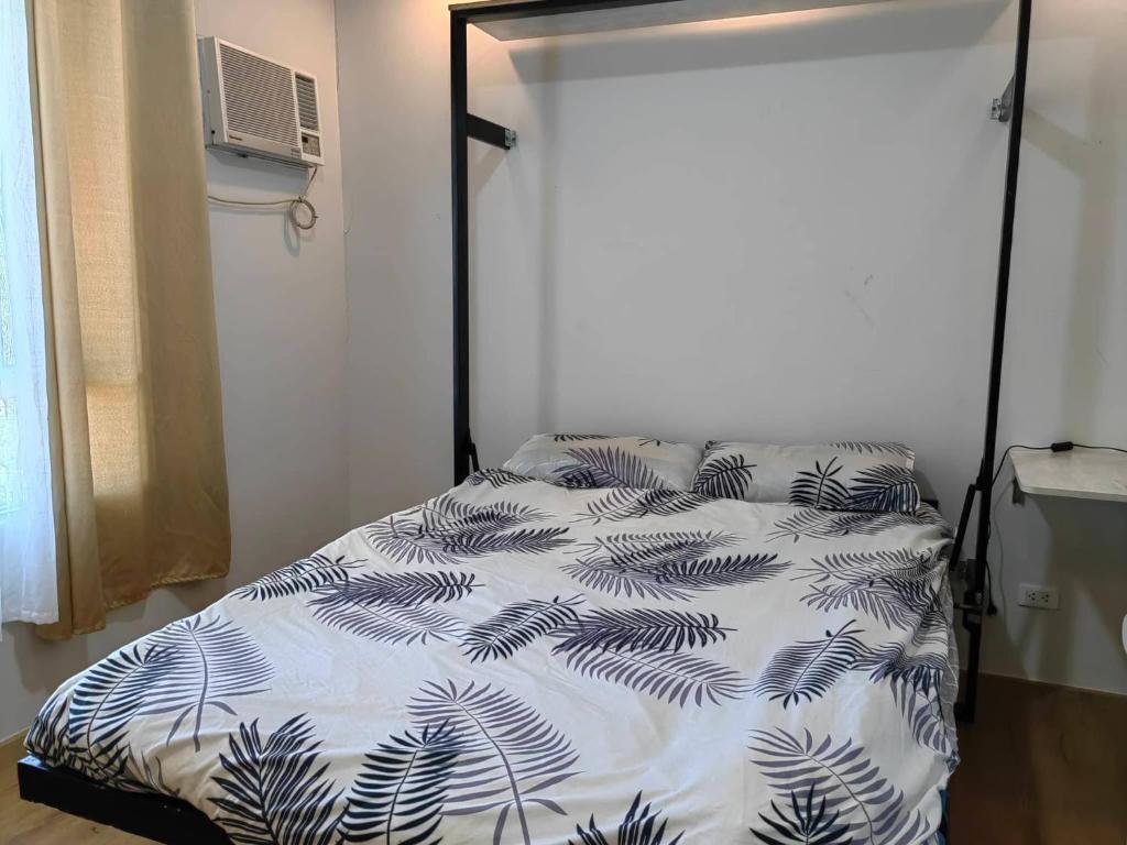 a bedroom with a bed with a white and black comforter at Mesatierra Garden Residences - Condo in Davao City