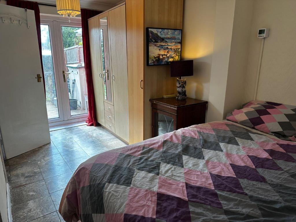 ein Schlafzimmer mit einem Bett mit einer Decke darauf in der Unterkunft Heathrow28 in West Drayton