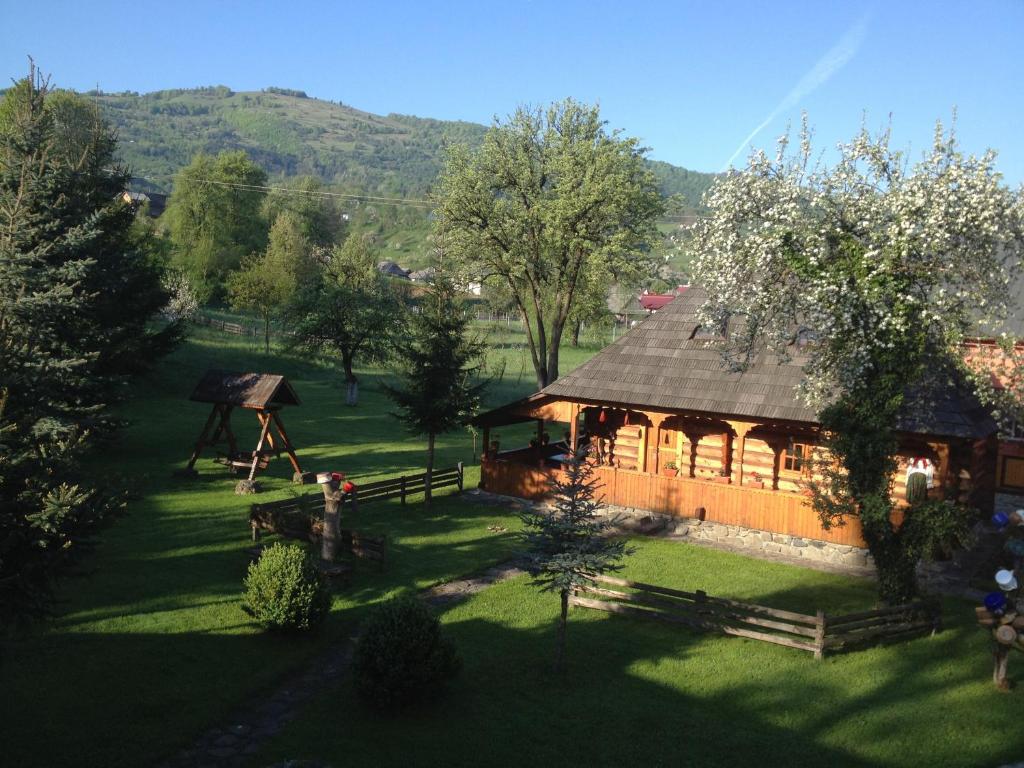 a large wooden cabin in the middle of a field at Pensiunea Turlas Maria in Săliştea de Sus