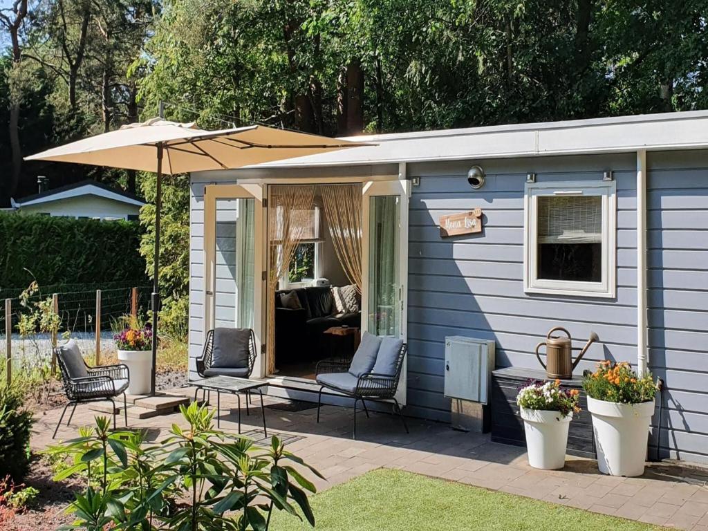 a blue tiny house with chairs and an umbrella at Cosy holiday home in Hattemerbroek with garden in Hattemerbroek