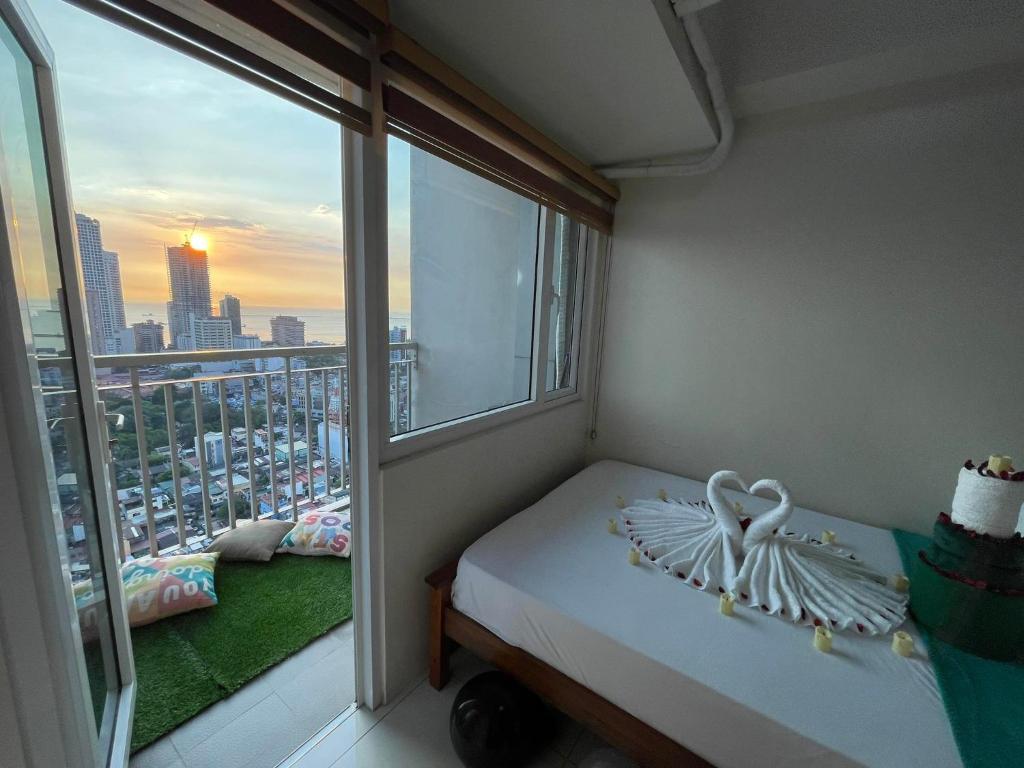 馬尼拉的住宿－Green Residences Stays by PBYY，客房设有一张床和一个享有城市美景的窗户。
