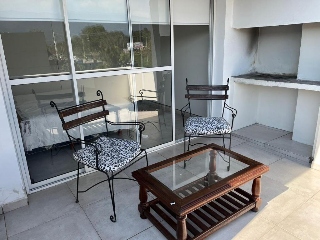 two chairs and a coffee table on a balcony at Departamento con Vista a los cerros con Asador in Yerba Buena