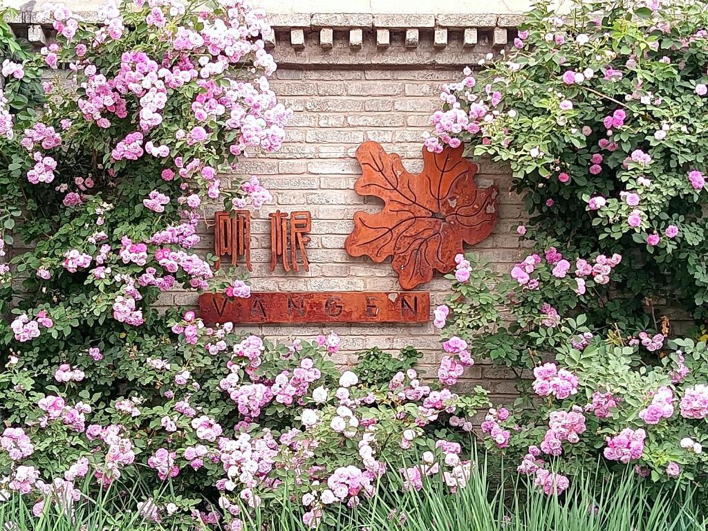 una pared de ladrillo con flores rosas y una mariposa en ella en Vangen Hotel, en Miyun