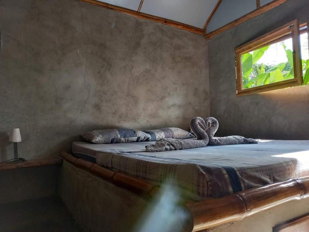a bedroom with a large bed with a window at Native Bungalows in El Nido