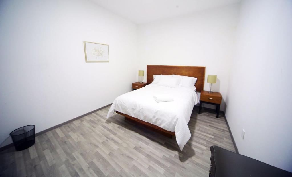 een slaapkamer met een wit bed en 2 nachtkastjes bij DEPA REMODELADO CENTRO HISTÓRICO ROOF GARDEN CON ESTACIONAMIENTO in Zacatecas