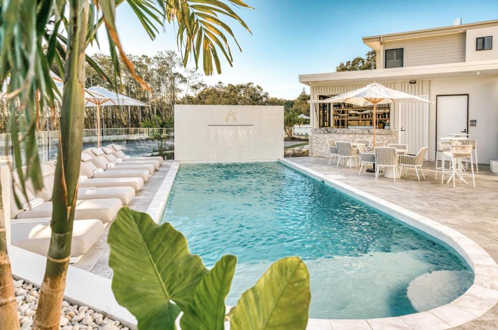 a swimming pool with chairs and a table in front of a house at Essence Boutique Hotel in Peregian Beach