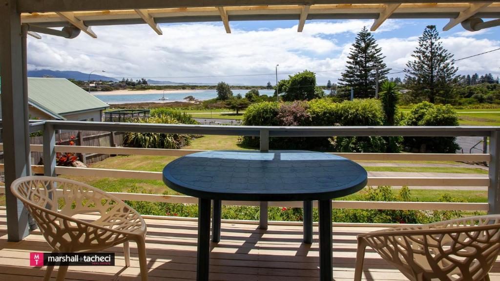 - une table et deux chaises sur une terrasse couverte offrant une vue sur l'eau dans l'établissement Aberdeen Unit 1 Bermagui, à Bermagui