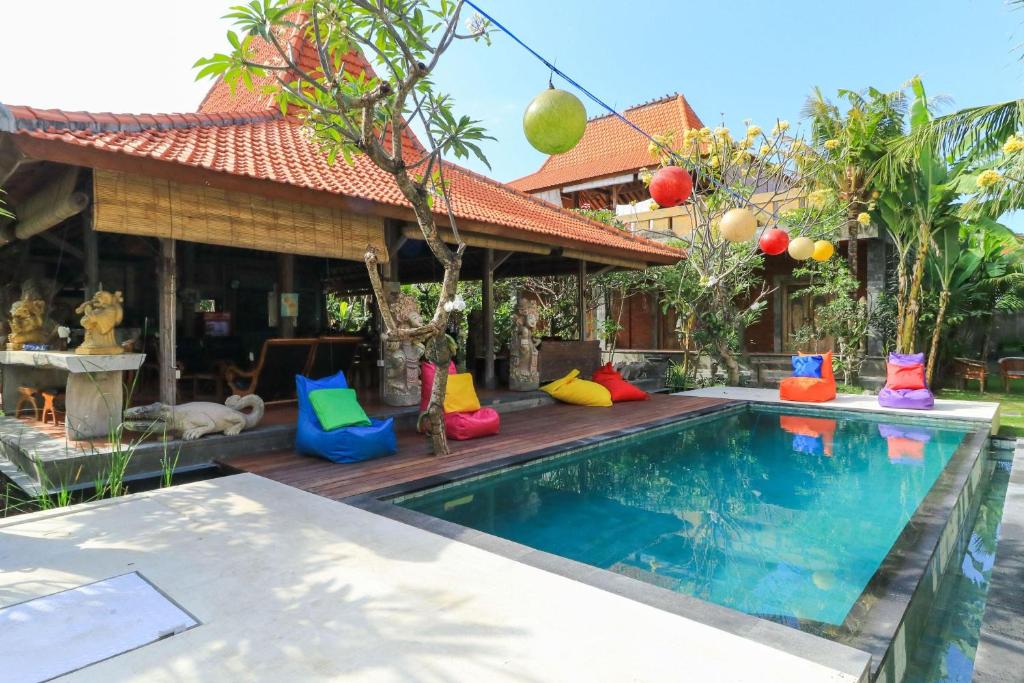 a pool with colorful pillows next to a house at Diuma residence yoga meditation retreat and healing Center in Denpasar