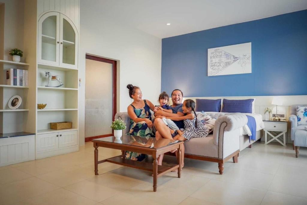a family sitting on a couch in a living room at The Cavalli Casa Resort in Phra Nakhon Si Ayutthaya