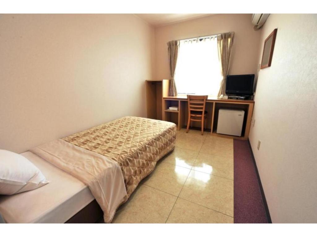 Schlafzimmer mit einem Bett, einem Schreibtisch und einem Fenster in der Unterkunft Hotel Yamadaso - Vacation STAY 10177v in Nago
