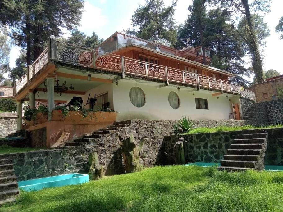 uma casa com uma varanda no topo de uma colina em Hermosa cabaña vista al bosque em La Marquesa