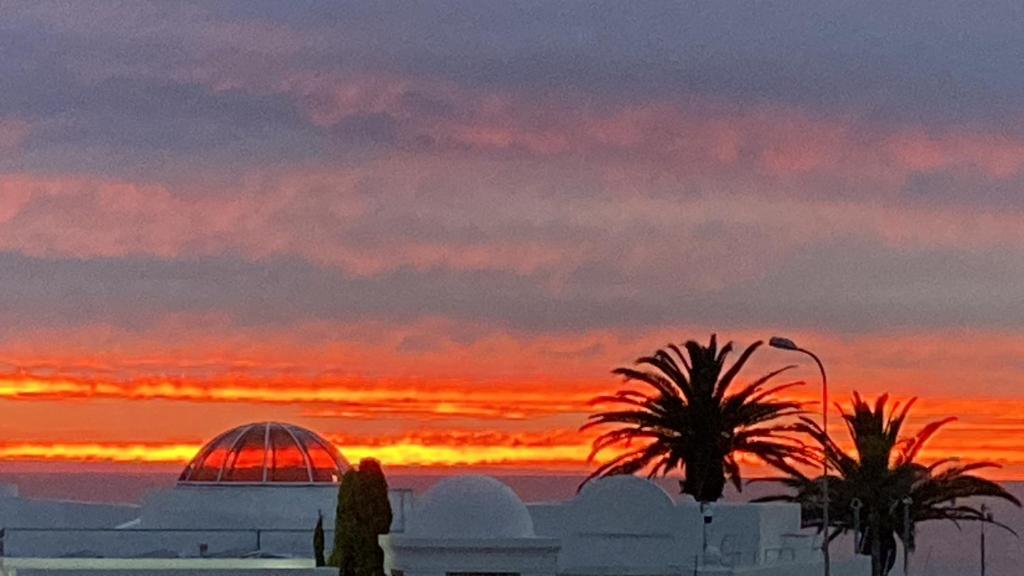 a sunset over a city with palm trees and a building at Secure apartment, 500m from the beach Cathcart Road, Humewood in Summerstrand