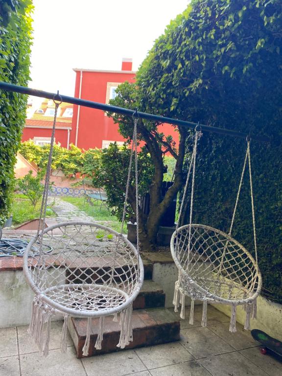 2 sillas colgantes en un jardín con escalera en SEA Villa Rosa Charm Seaside and Garden en Oporto
