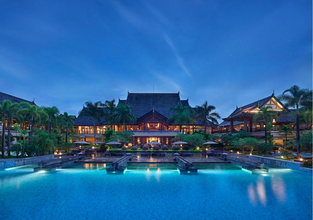 a large pool in front of a resort at night at Anantara Xishuangbanna Resort in Jinghong