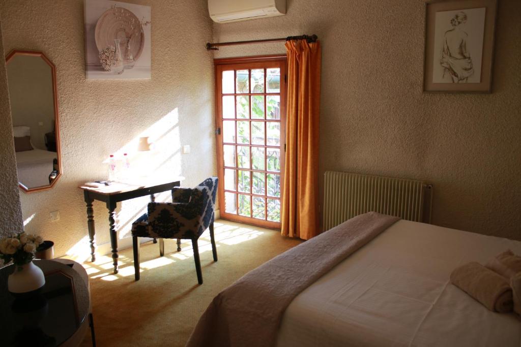 Schlafzimmer mit einem Bett, einem Schreibtisch und einem Fenster in der Unterkunft La Passiflore in Vergèze