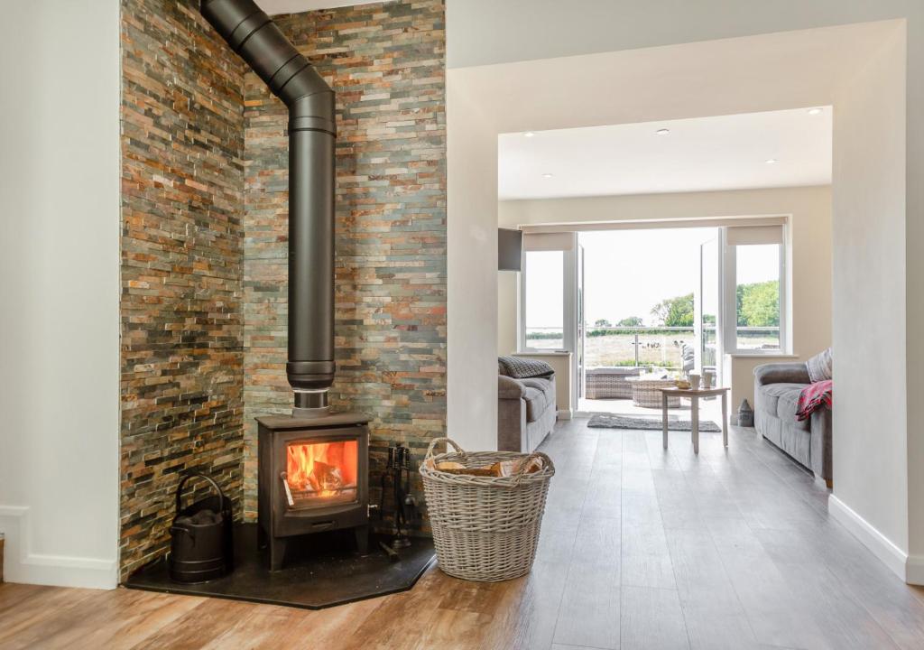 a fireplace in a living room with a brick wall at Yr Hen Barlwr in Llanddyfnan