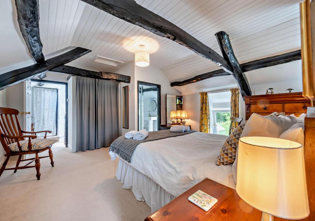 LlangelerにあるOld Vicarage Cottageのベッドルーム(大型ベッド1台、椅子付)