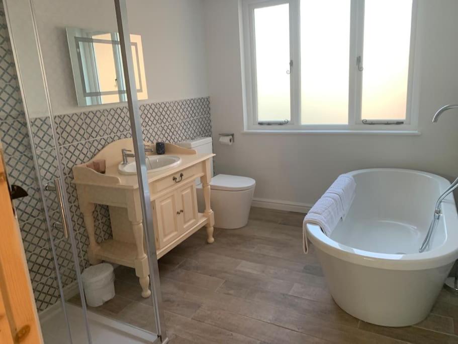 a bathroom with a tub and a sink and a toilet at Cottage with outstanding views in Velindre