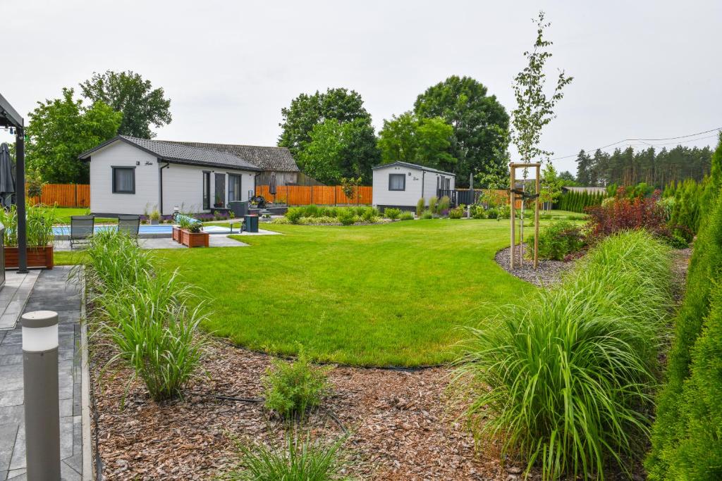 een tuin met een huis en gras bij Barszczówka - domki, basen podgrzewany, prawdziwe jacuzzi, sauna infrared i inne atrakcje na Podlasiu in Kłyżówka