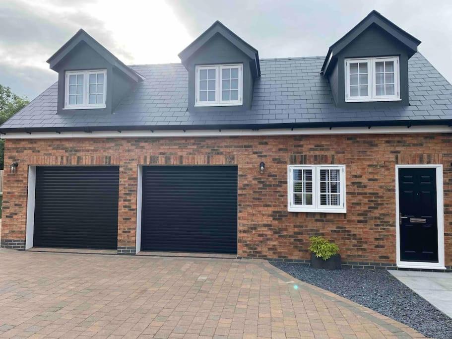 a brick house with two garage doors at The Lodge at Crown Point, Entire Place, Private Secure Parking, EV Point, Brand new in Hillmorton