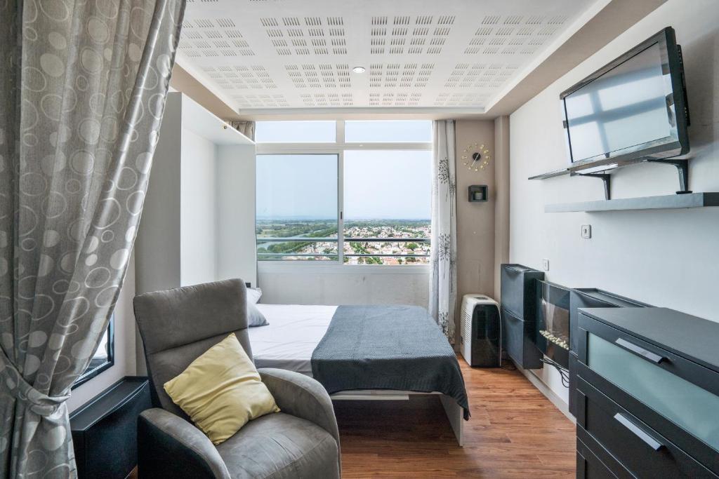 Cette petite chambre comprend un lit, une chaise et une fenêtre. dans l'établissement Apartamento Welcs EMP- 090-con vistas, à Empuriabrava