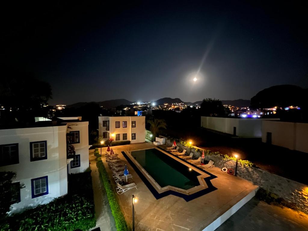 a view of a house with a pool at night at Ege Apartments in Yalıkavak