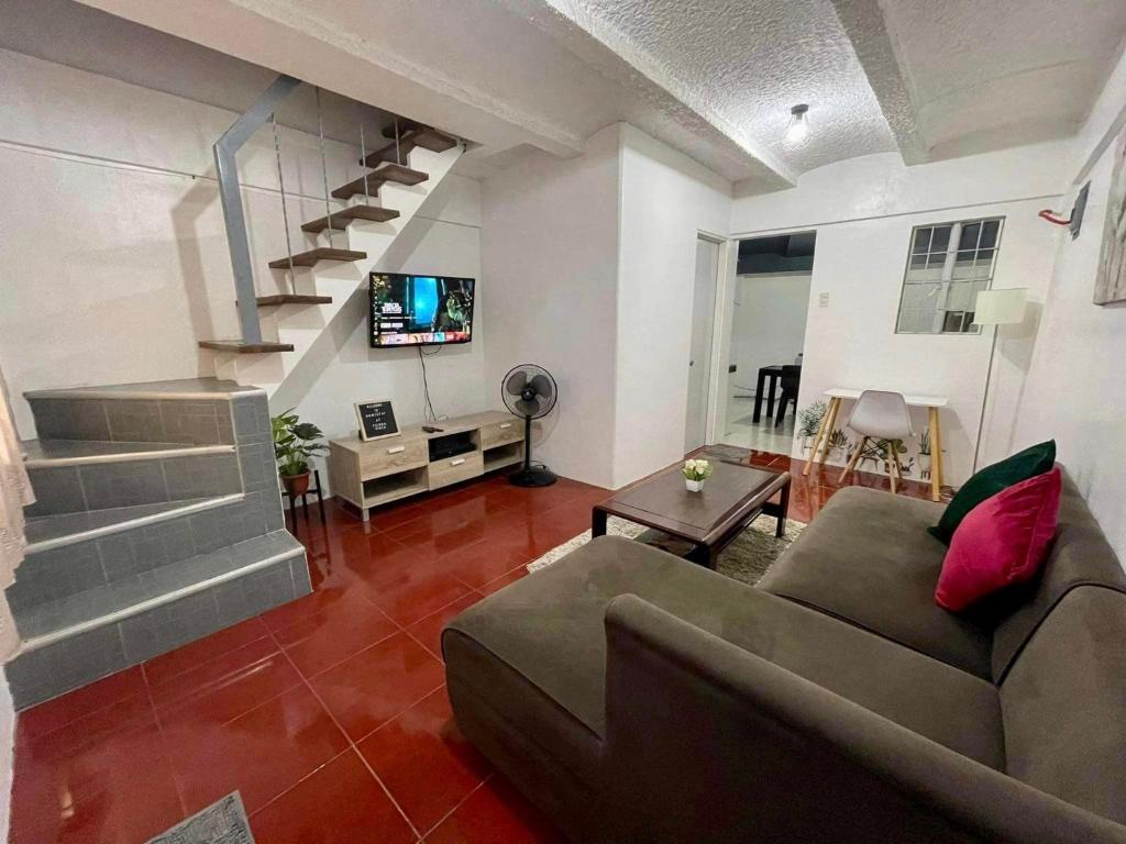 a living room with a couch and a staircase at Transient Home at Tierra Vista near SM Dasma with Wifi and Netflix in Mabatang