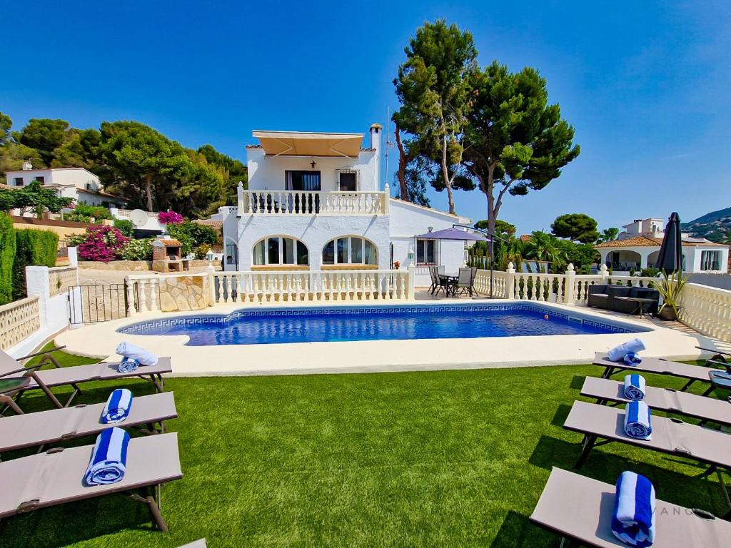 a villa with a swimming pool and lawnitures at Villa cerca del pueblo y playas de Moraira - Ref A022 AVANOA PREMIUM RENTALS in Moraira