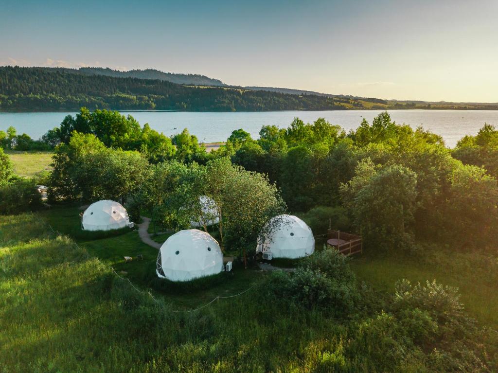 una vista aérea de tres cúpulas en un campo junto a un lago en Biała Czapla Glamping z balią nad jeziorem czorsztyńskim en Maniowy