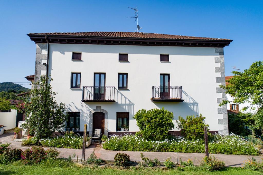 a white house with black windows and balconies at Altamira, SEA & MOUNTAIN in Busturia